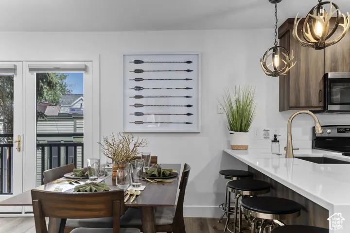 Open-concept living space with dual pendant lighting, wood-finish flooring, white countertop island, and wood-finish cabinetry