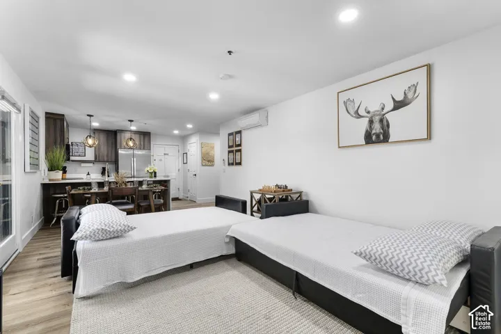 Open-concept living space featuring wood-finish flooring, recessed lighting, and a kitchen with dark-toned cabinetry, stainless steel appliances, and a central island with pendant lighting