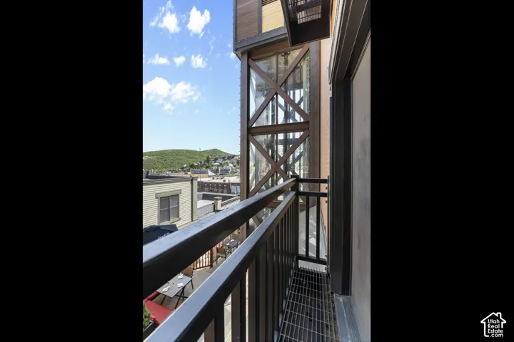 Exterior balcony with metal railing, open-grate flooring, and a multi-story window feature