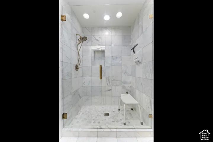 Glass-enclosed shower with white tiled walls and mosaic tile flooring