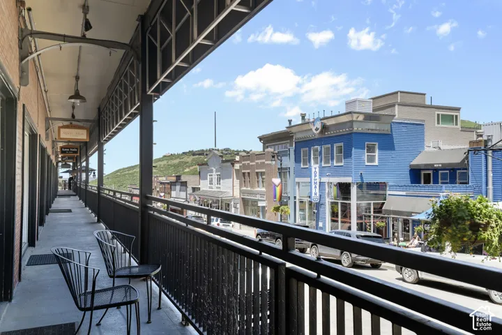 Covered pedestrian walkway with a black metal railing and overhead lighting fixtures