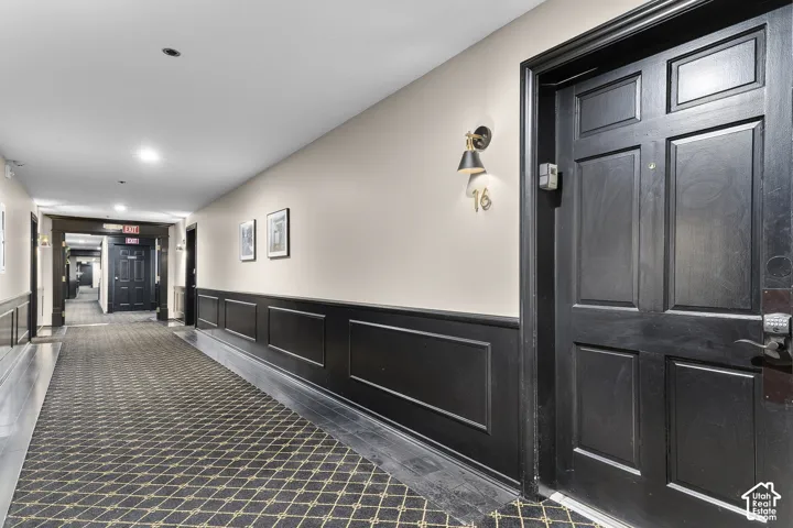 Corridor featuring wainscoting, recessed lighting, and patterned carpeting