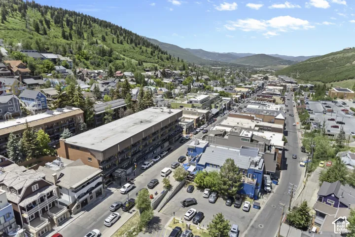 Mountainous backdrop, extensive commercial and residential structures, dense tree coverage, paved roadways, and multiple parking areas