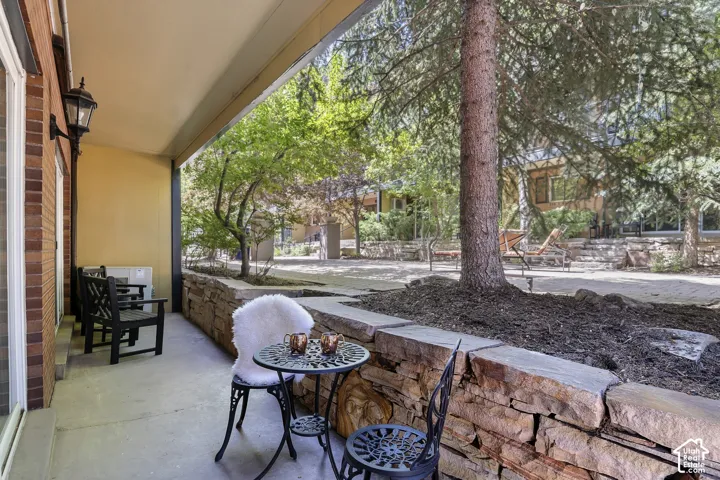 Covered patio with a concrete surface, featuring an exposed brick wall and an exterior sconce