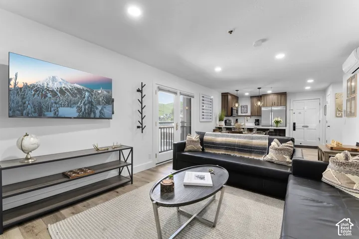 Open-concept living area featuring wood-finish flooring, recessed lighting, and a kitchen with wood cabinetry, stainless steel appliances, and pendant lighting