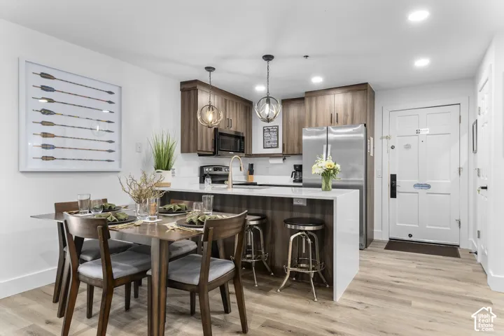 Wood-finish flooring throughout, kitchen with wood-finish cabinetry, stainless steel appliances, and a white countertop island with seating