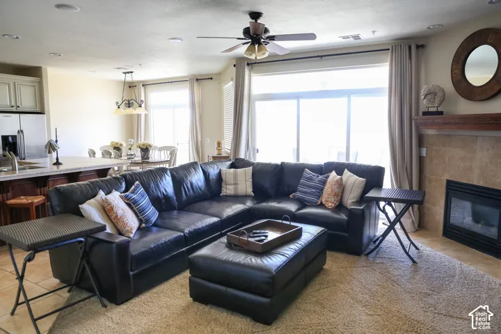 Spacious living area featuring a ceiling fan, fireplace with a tile surround and wood mantel, large sliding glass doors, and recessed lighting