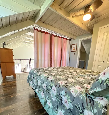 Vaulted ceiling with exposed beams, wood-finish flooring, ceiling fan with integrated lighting, interior door