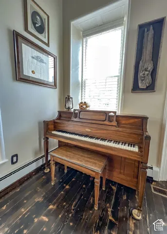 Dark-toned wood flooring, natural light window with blinds, and white wall finishes