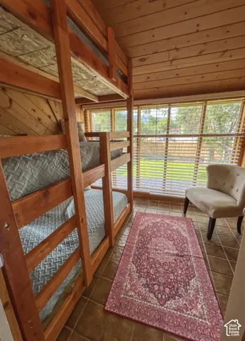 Wood-paneled walls and ceiling, multiple large windows, and tile flooring