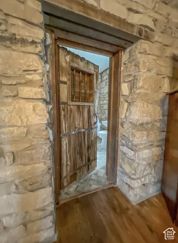 Exposed stone wall construction with wood flooring and a rustic wood-plank door with metal hardware
