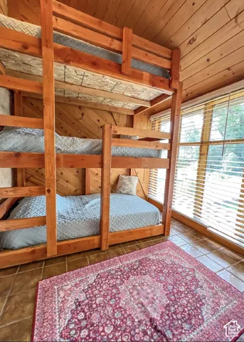 Built-in wood bunk beds, wood-paneled walls, wood-paneled ceiling, and tiled flooring