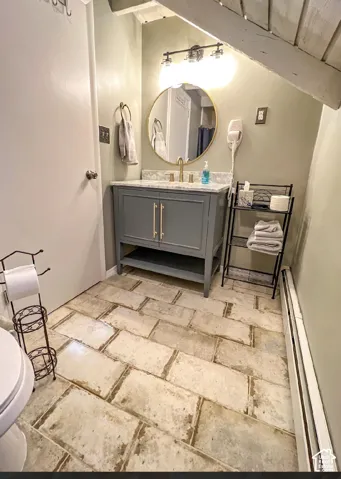 Vanity with a light-colored countertop, gold-finish faucet, and a round mirror