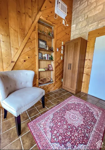 Wood-paneled wall with built-in shelving, stone accent wall, tile flooring, and a compact air conditioning unit