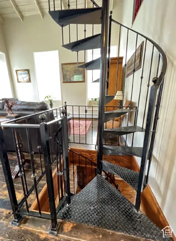 Black spiral staircase with diamond plate treads and wrought iron balusters, complemented by exposed wood ceiling beams