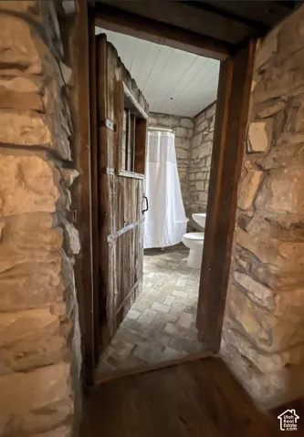 Stone wall construction with a paneled wood door and wood-finish flooring