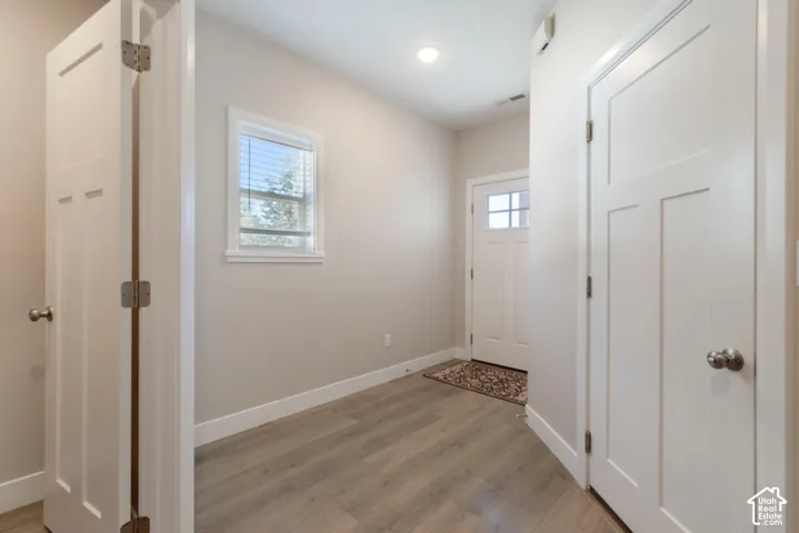 Entryway featuring wood-finish flooring, a window with blinds, and white doors with brushed nickel hardware