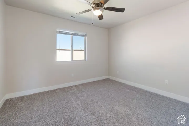 Plush gray carpeting, neutral wall finishes, and a ceiling fan with integrated lighting