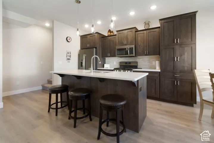 Wood-finish flooring throughout, dark wood-finish cabinetry, stainless steel appliances, light-toned countertops, and recessed lighting