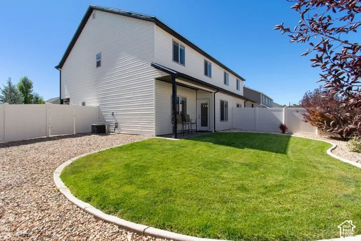 Manicured lawn, gravel landscaping, privacy fencing, covered patio, and exterior lighting