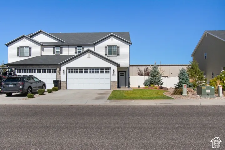 Two-story residence featuring white siding, black window shutters, a two-car garage, an additional single-car garage, and a manicured lawn