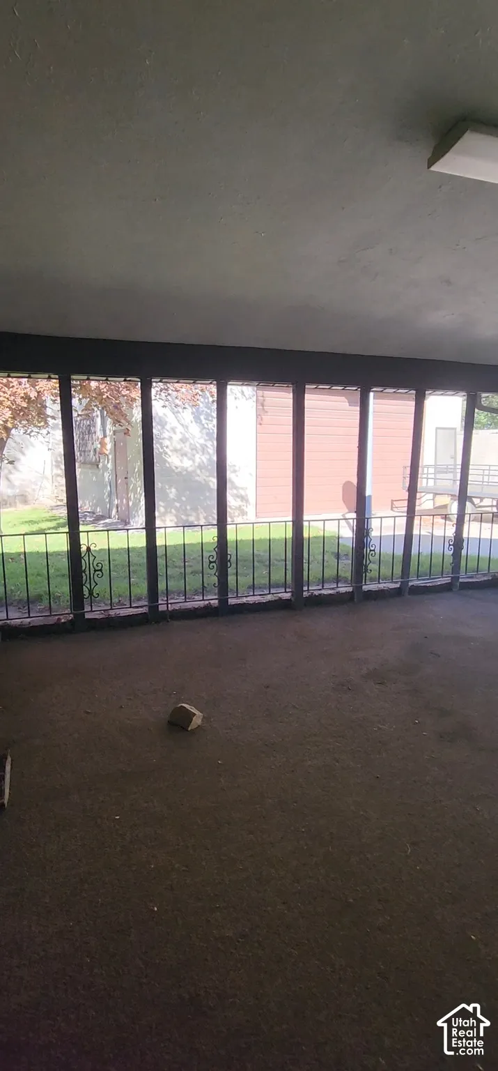Enclosed patio with full-height windows, decorative metal railings, and a flush-mount ceiling light fixture