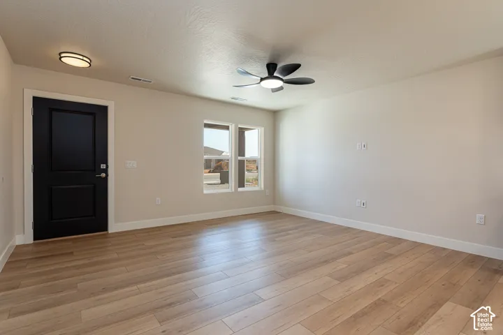 Wood-finish flooring, recessed lighting, ceiling fan, and multiple windows with white trim