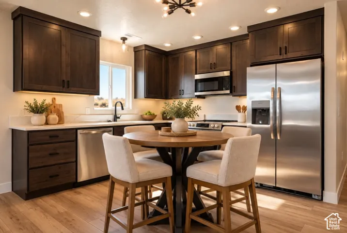 Dark wood-finish cabinetry, stainless steel appliances, light-toned countertops, wood-finish flooring, and recessed lighting