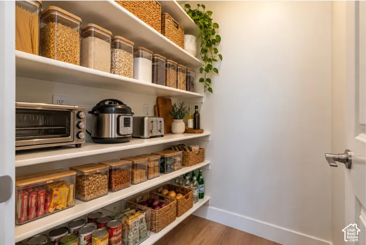 Full-height shelving, wood-finish flooring, white walls, and a white interior door with brushed nickel hardware