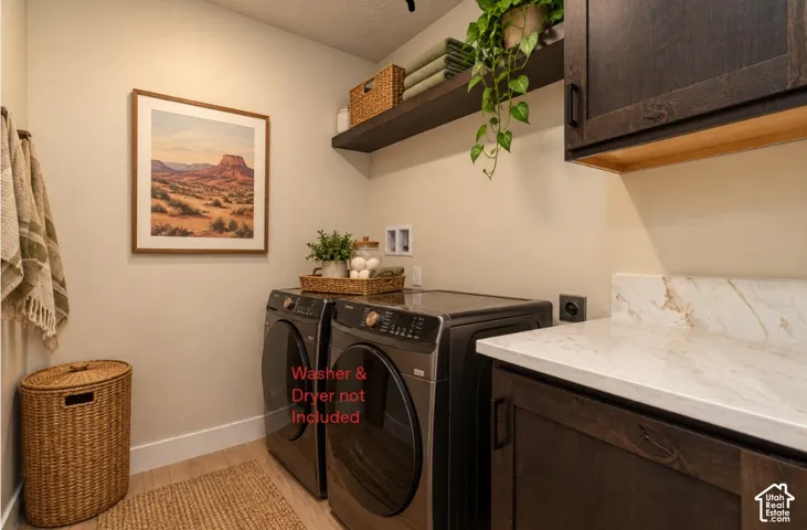Wood-finish flooring, dark wood cabinetry, white countertop with veining, and a floating shelf