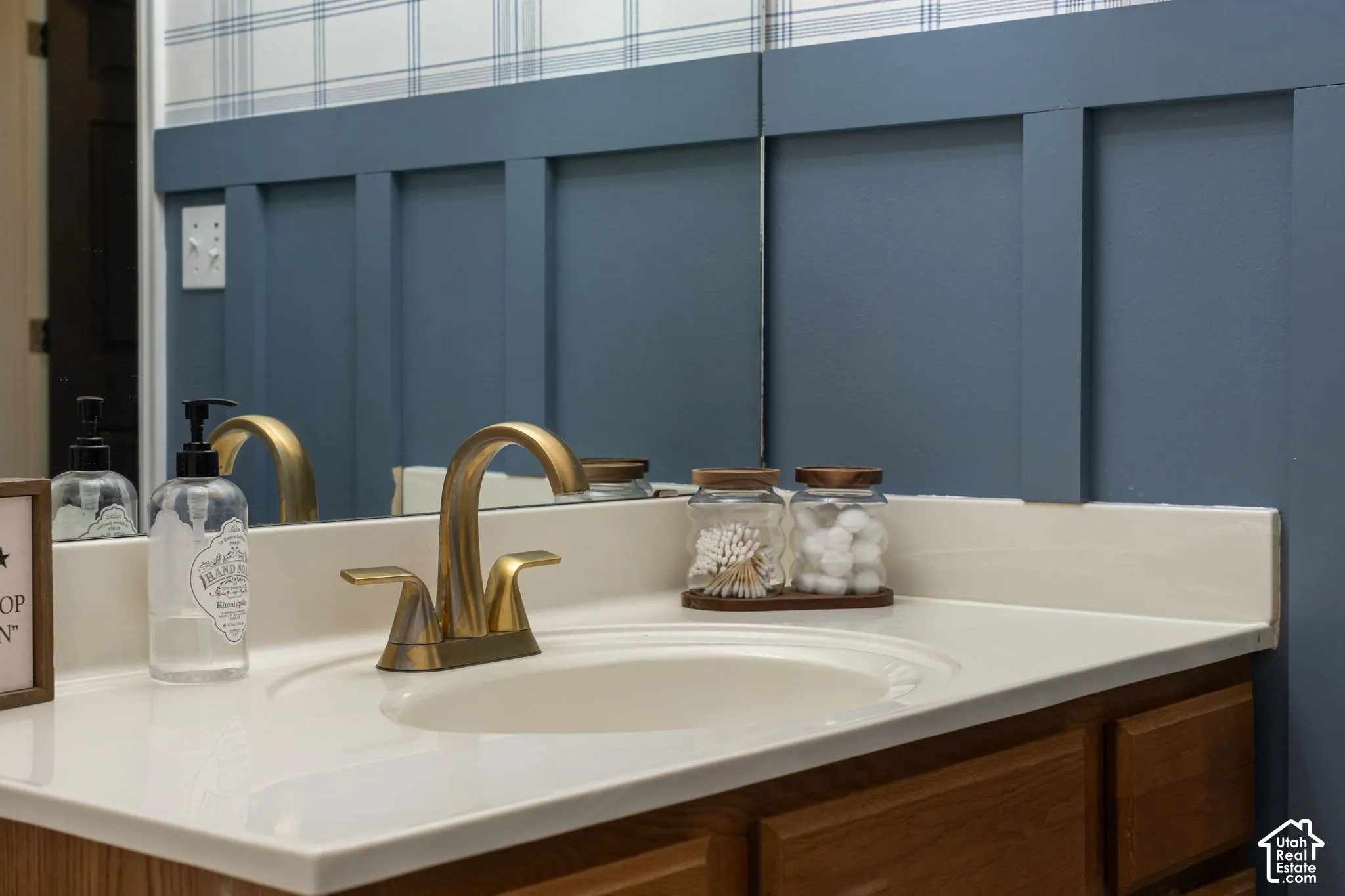 Built-in vanity with a single basin sink, brass-finish faucet, and light-toned countertop