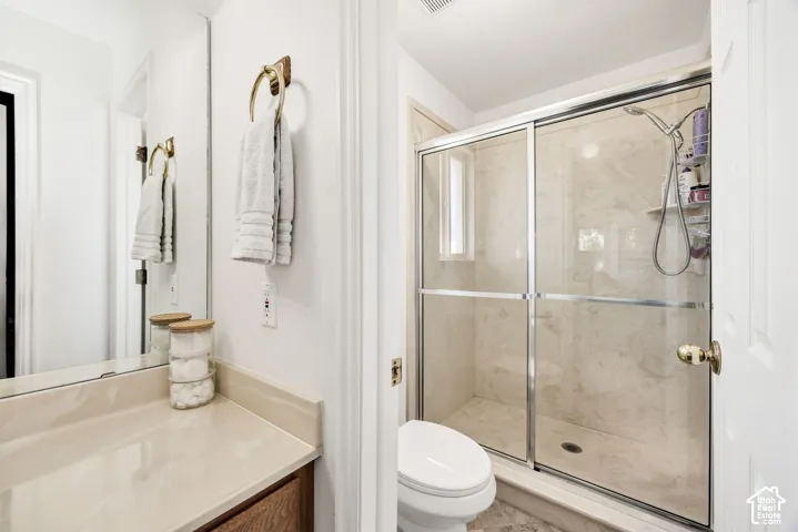 Ensuite vaulted ceiling with a ceiling fan, plush carpeting, built-in vanity.