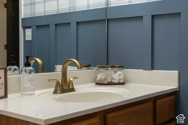 Built-in vanity with a single basin sink, brass-finish faucet, and light-toned countertop