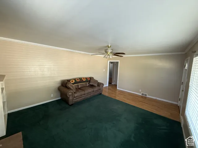 Crown molding throughout, ceiling fan with integrated lighting, wood-finish flooring, built-in shelving, and window with blinds