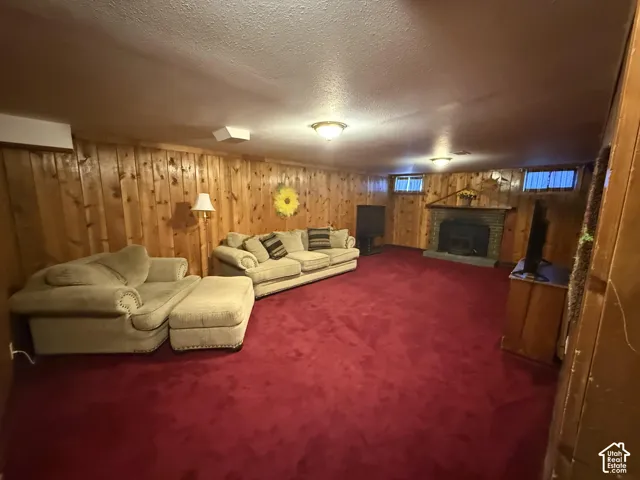 Finished basement featuring wood paneling, red carpeting, a brick fireplace, and built-in ceiling lighting