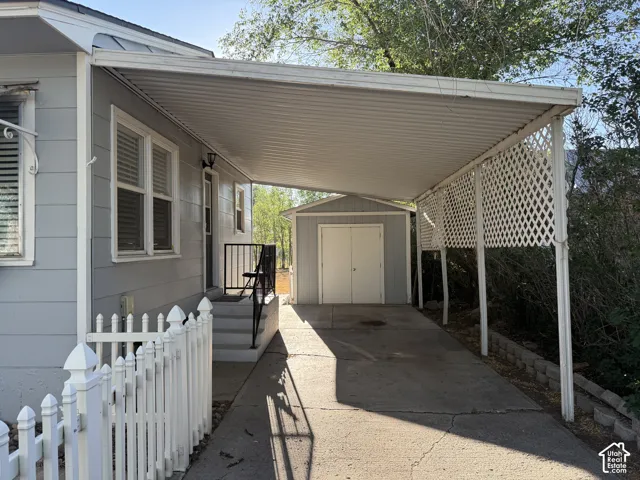 Covered carport with metal roof and lattice privacy screening, attached to light blue siding home with white trim and multi-pane windows