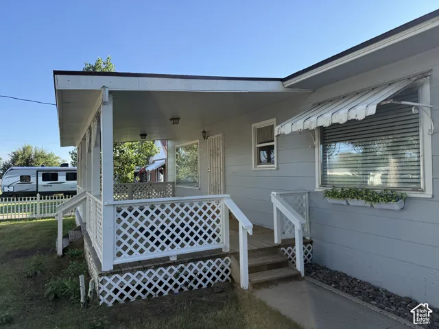Covered front porch with white lattice detailing, wood-finish decking, and an awning over a large window