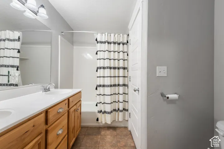 Dual vanity with integrated sinks, light wood-finish cabinetry, and a large wall-mounted mirror