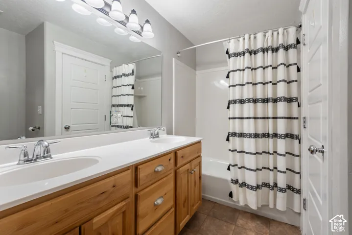 Double vanity with wood-finish cabinetry, chrome fixtures, and a white countertop
