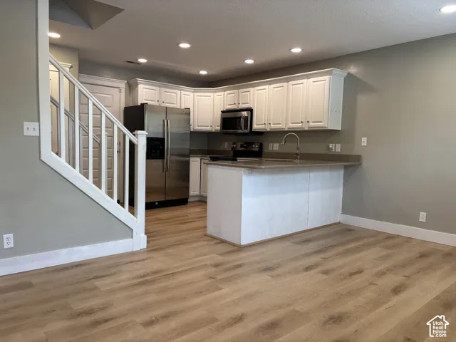 Kitchen featuring white cabinetry, stainless steel appliances, a breakfast bar, and recessed lighting