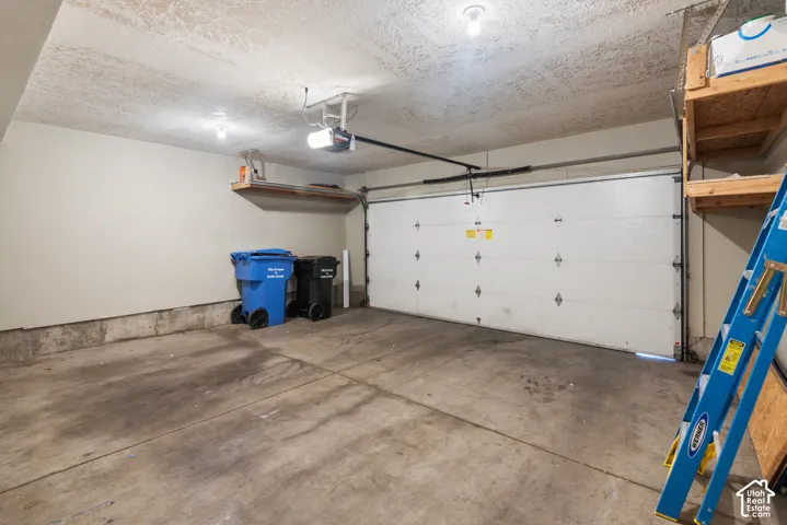 Attached garage featuring a concrete floor, overhead lighting, and built-in shelving