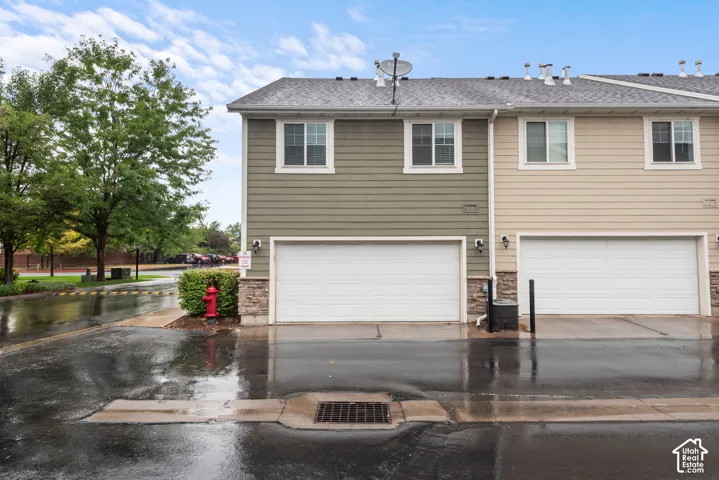 Two-story exterior with horizontal siding, stone veneer accents, and individual garage doors