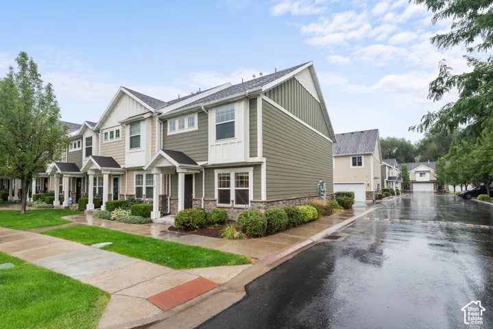 Townhome exterior featuring varied siding materials, gabled roofs, stone veneer accents, covered entryways, and manicured landscaping