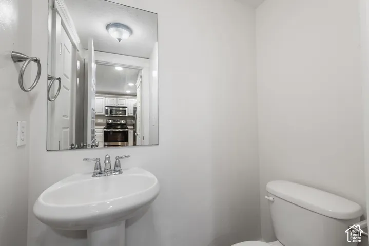 Pedestal sink with chrome faucet, wall-mounted mirror, and white toilet