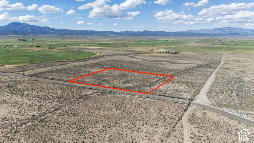 Expansive undeveloped land with a mountain backdrop, featuring a dry, vegetated terrain and a clear sky