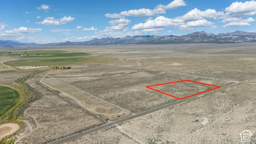 Expansive undeveloped land with direct road frontage, surrounded by natural vegetation and distant mountain ranges