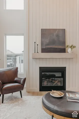 Floor-to-ceiling vertical plank wall cladding, fireplace with a black surround, natural wood-finish mantel, high ceilings, and tall rectangular windows