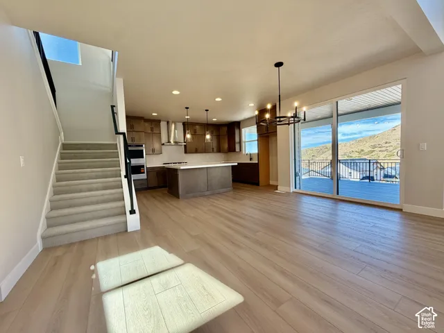 Spacious interior featuring wood-finish flooring, a contemporary kitchen with a central island, and a full wall of sliding glass doors