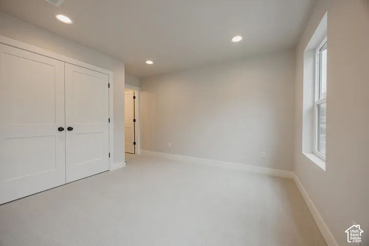 Room featuring neutral wall-to-wall carpeting, recessed ceiling lighting, and double-door closet with matte black hardware