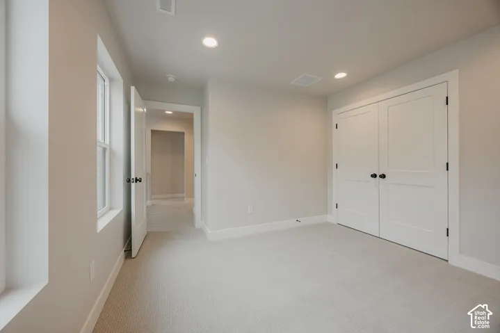 Interior space featuring neutral wall tones, recessed lighting, wall-to-wall carpeting, double-panel closet doors with matte black hardware, and an interior passage door
